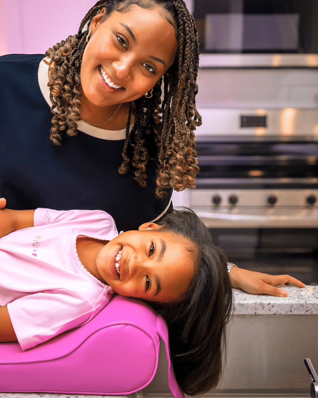 Woman and child in a kitchen, smiling at the camera